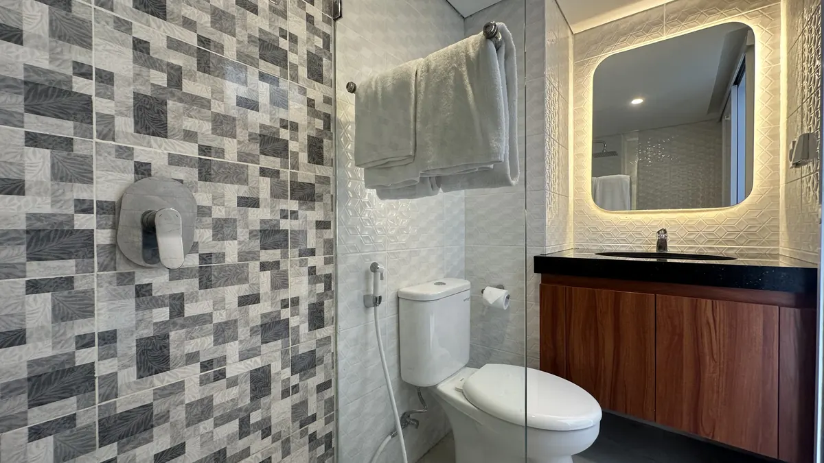 Bathroom with backlit mirror and stone-tile wall