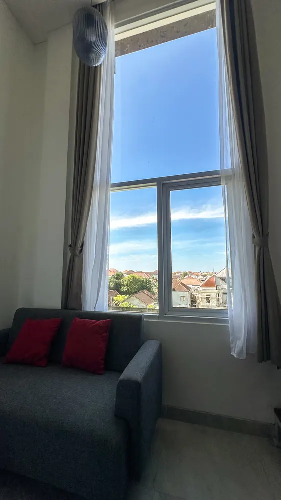 Sofa with red cushions below the tall window