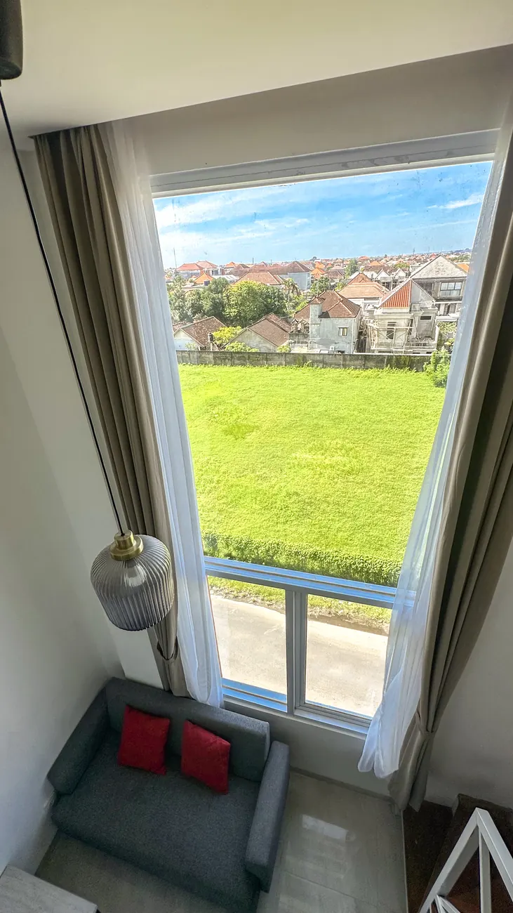 Double-height window looking out over open green fields